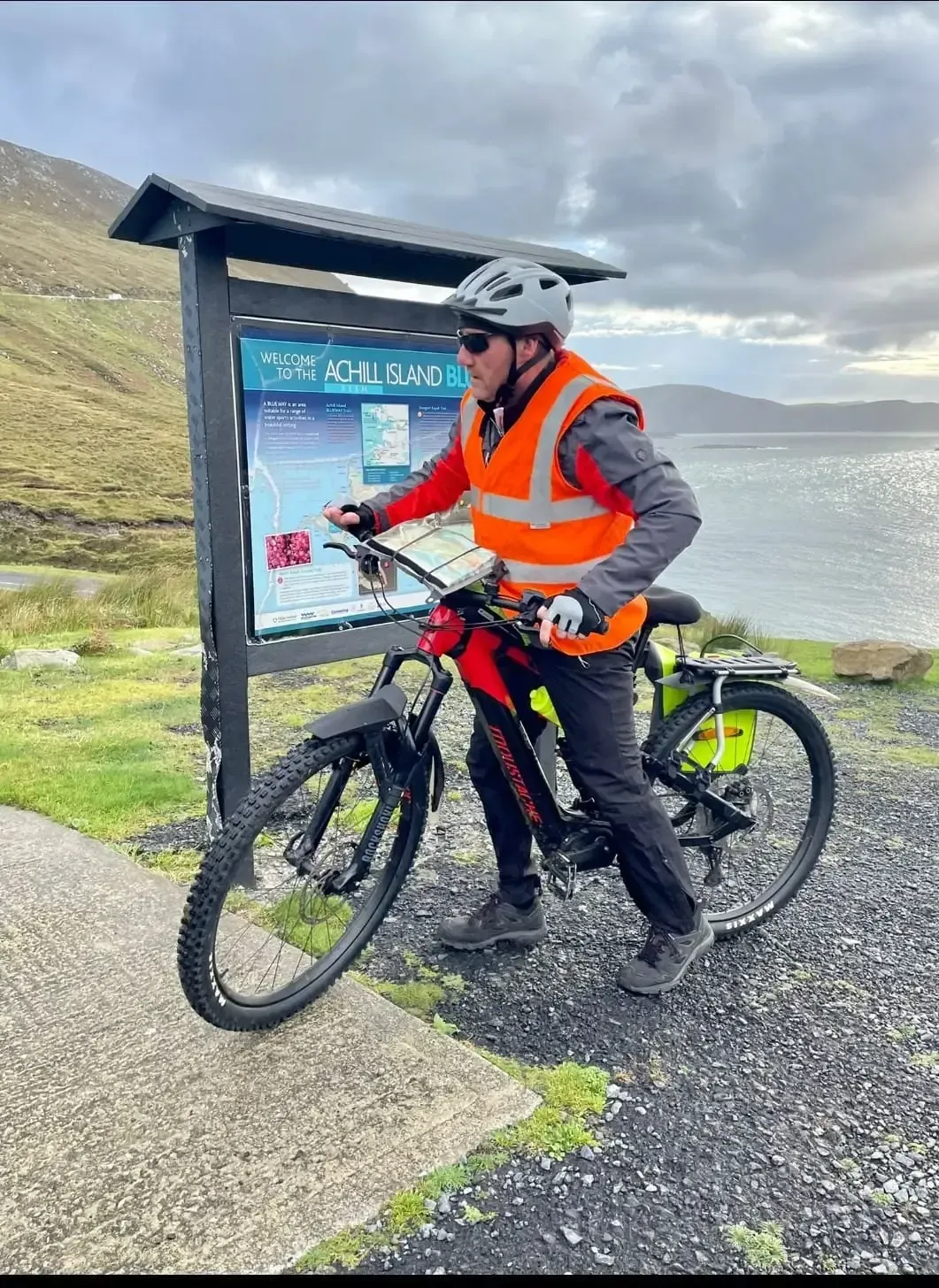 Paddle Northern Ireland | A man is riding an electric bike next to a sign.