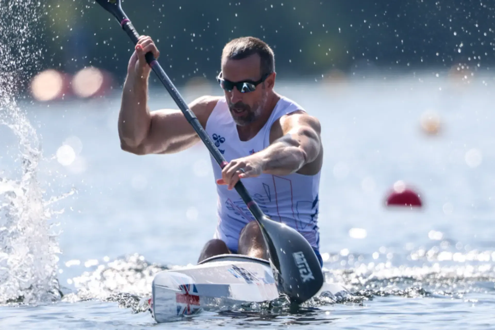 A man is paddling a kayak on a lake.
