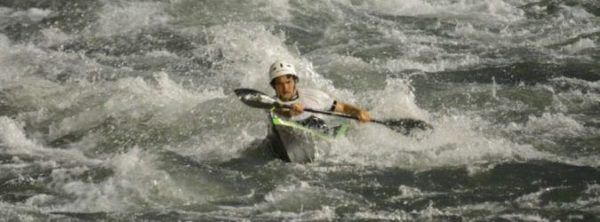 A man in a kayak is paddling through a river.