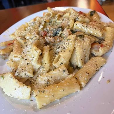 a white plate topped with pasta and sauce on a table