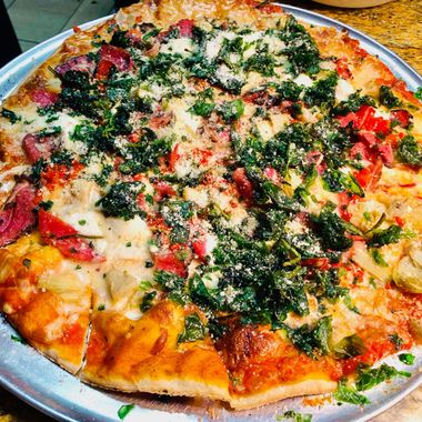 a pizza with a lot of toppings on it is on a pan on a table