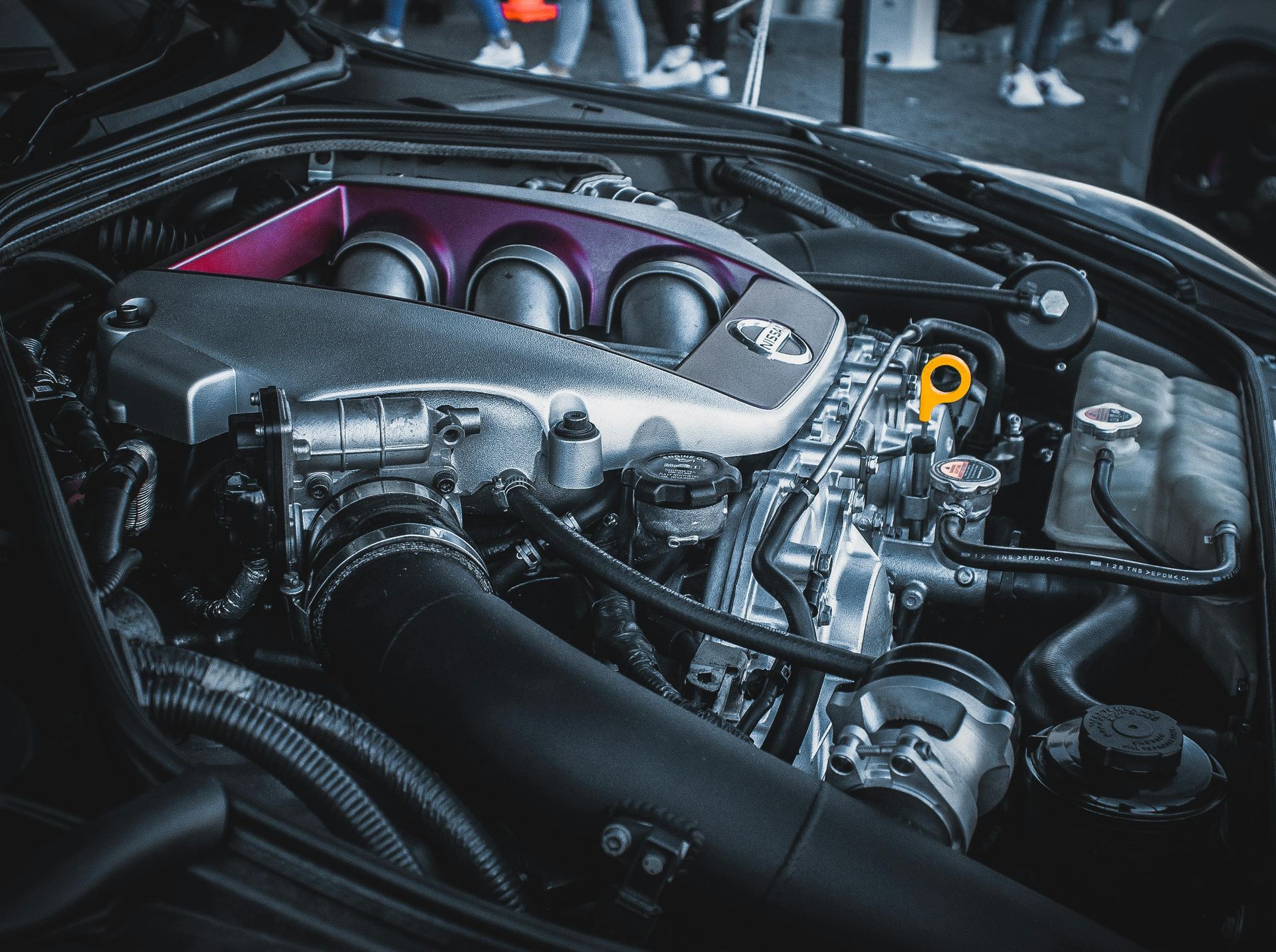 Car engine bay with a purple intake cover and yellow oil cap, viewed from above