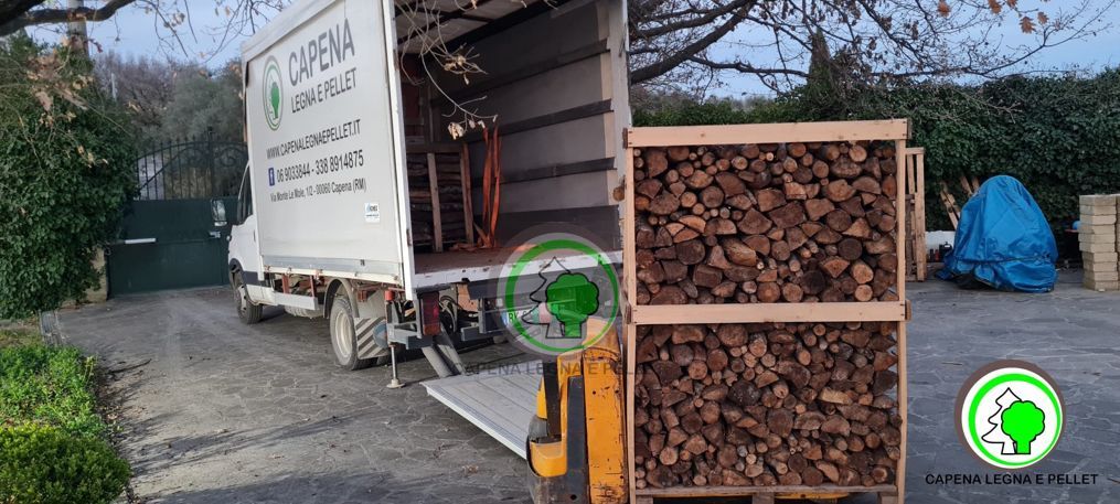 Un camion viene caricato su un pallet di legno pieno di legna da ardere in un'area all'aperto.