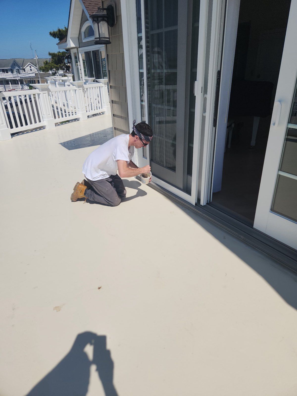 A man is kneeling down on a deck working on a sliding glass door