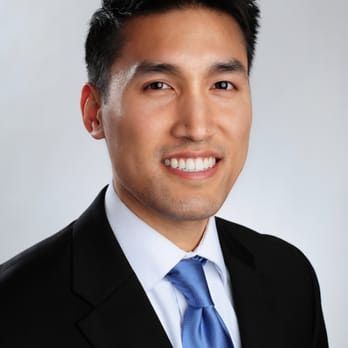 Man in suit smiles at the camera, wearing a blue tie.