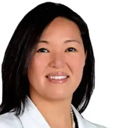 A smiling doctor in a lab coat with a stethoscope around his neck.