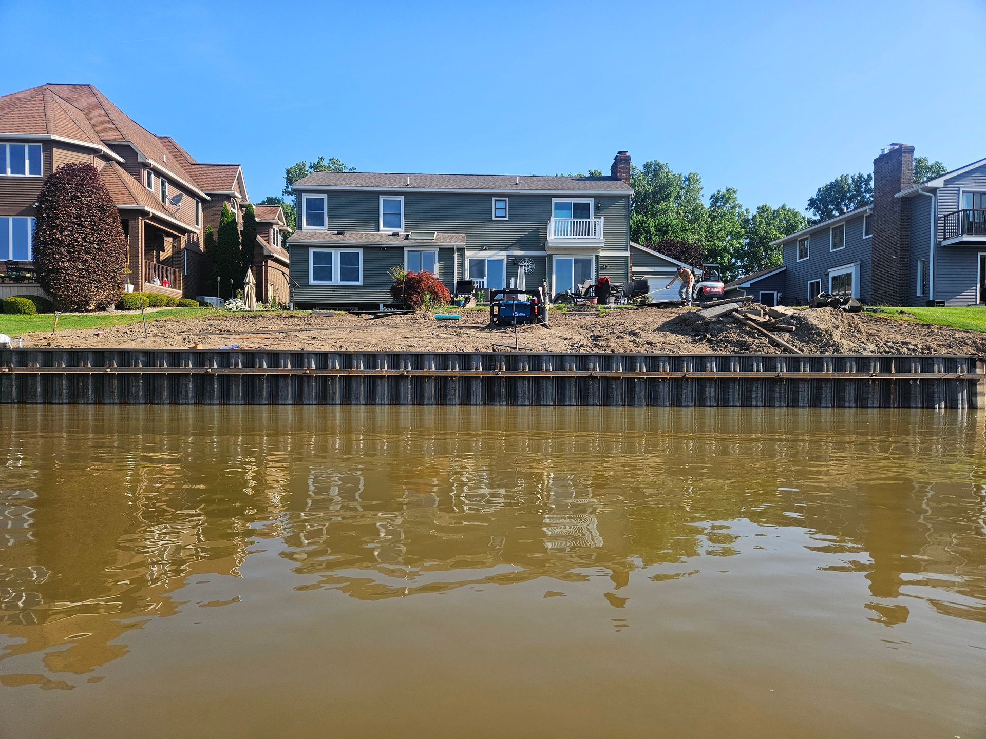 Waterfront house with orange siding and boats docked beside calm blue water Waterfront house with orange siding and boats docked beside calm blue water