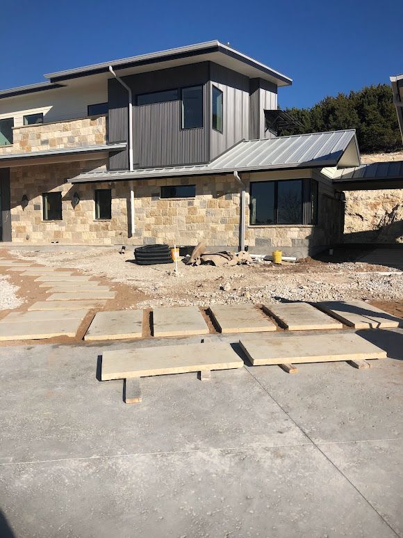 A brick wall is being built in a garden next to a sidewalk.