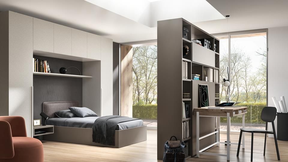 Camera da letto monolocale moderna con letto a soppalco, scrivania, mensole e ampie finestre con vista sugli alberi.