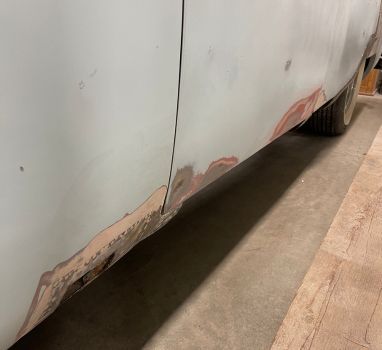 A white car is sitting on a wooden floor in a garage.