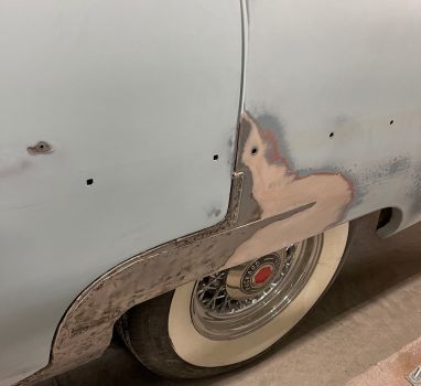 A white car with white tires is sitting in a garage.