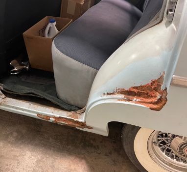A white car with rust on the side of it