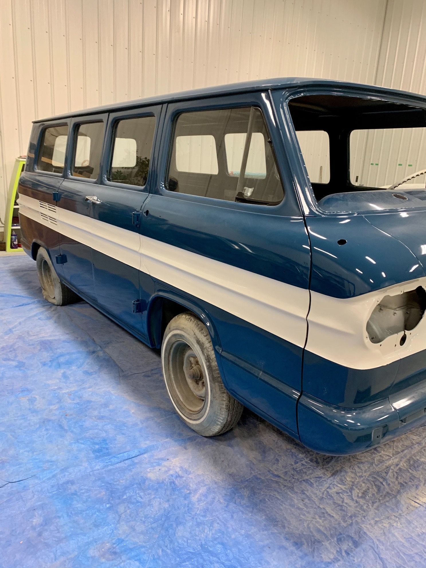 A blue and white van is parked in a garage.
