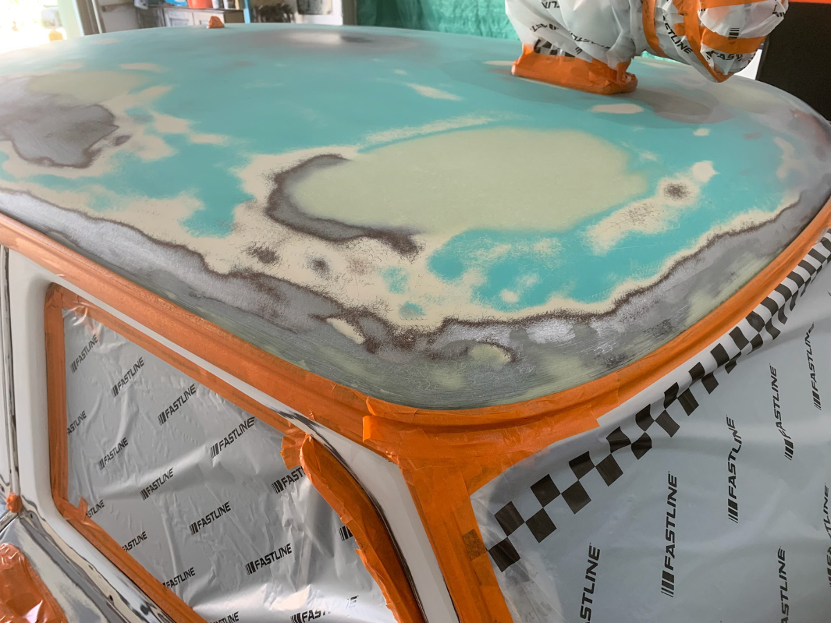 Close-up of a turquoise and gray custom car hood with orange trim and black-and-white checkered detailing