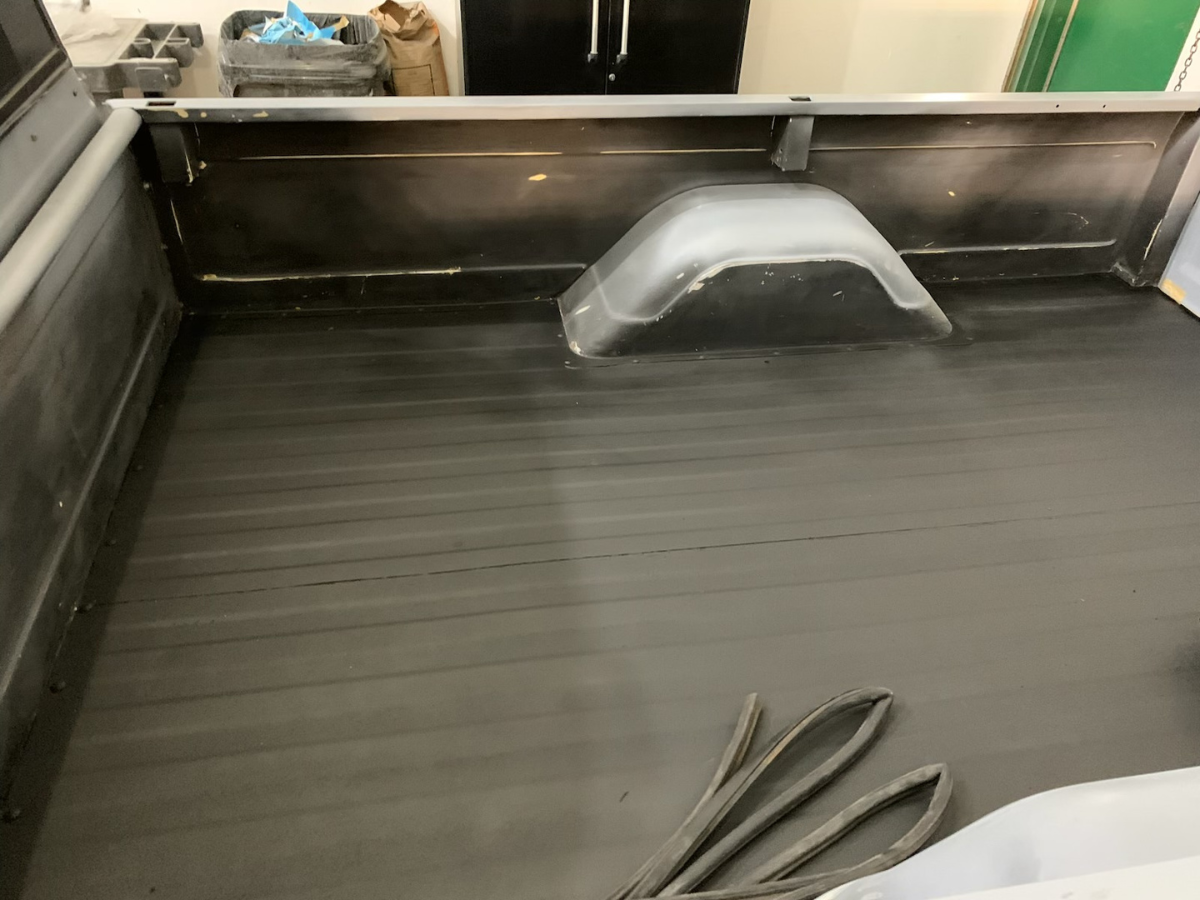 Empty black conveyor belt with a clear plastic cover near the back and a coiled strap in the foreground