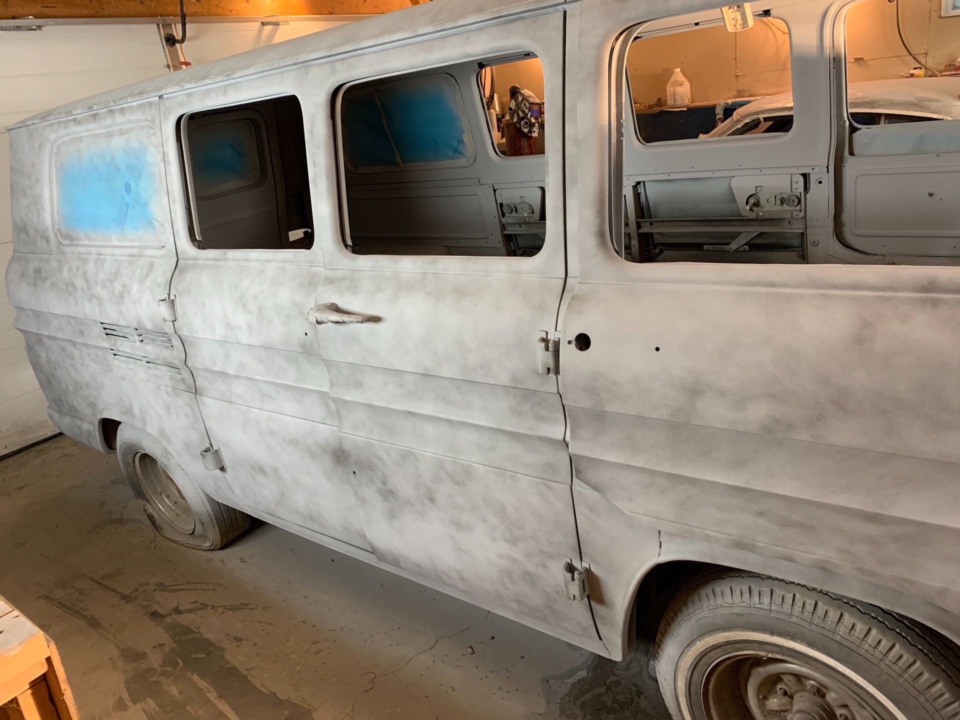 An old white van is sitting in a garage.