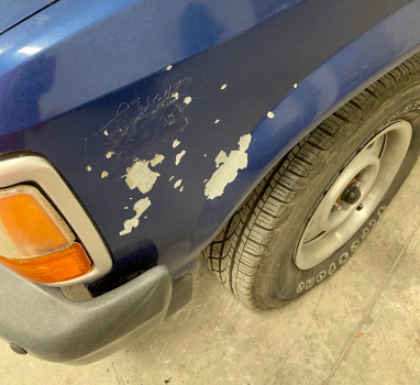A blue car with a tire that says bfgoodrich on it