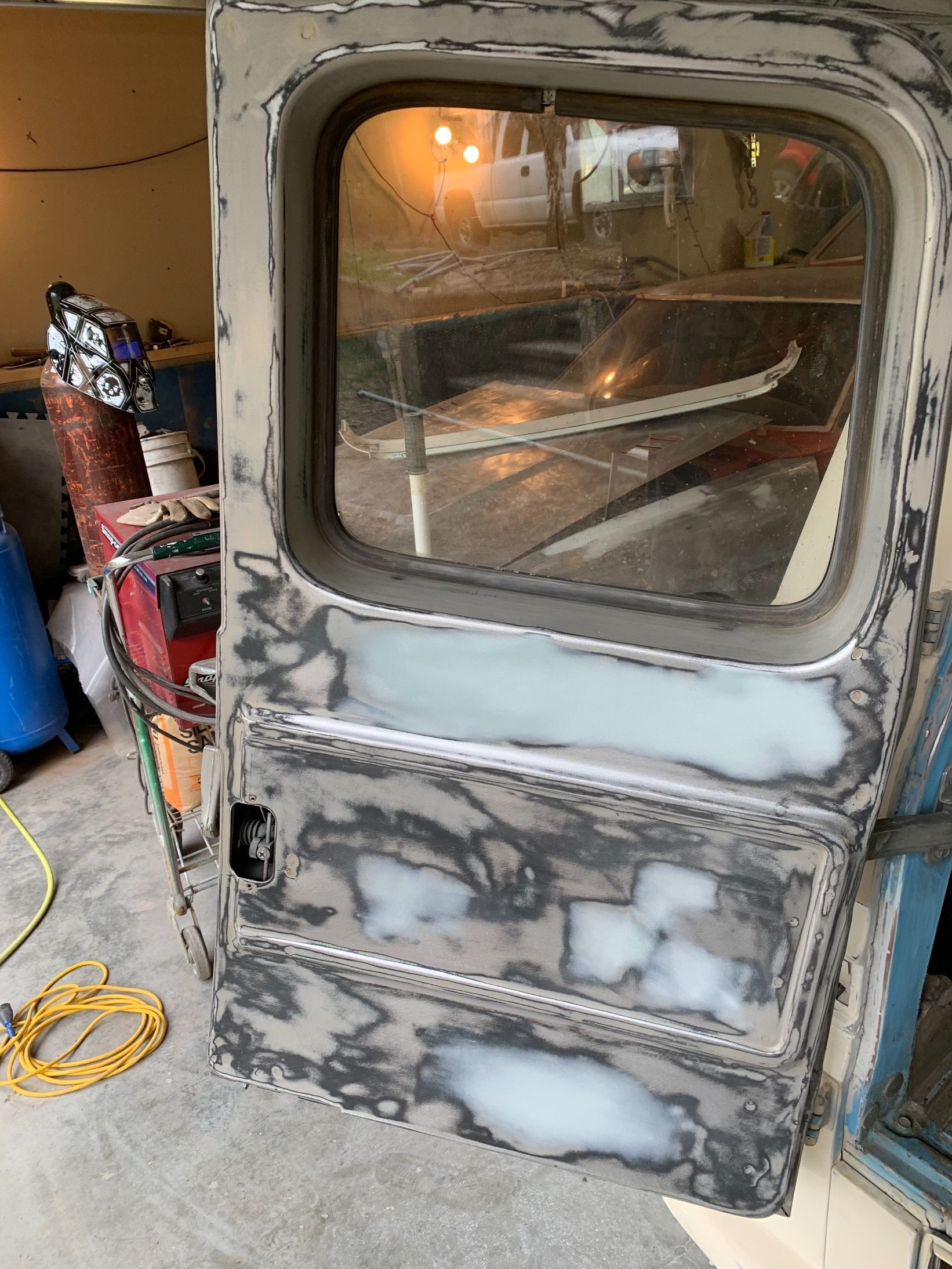 A door with a window is being repaired in a garage.