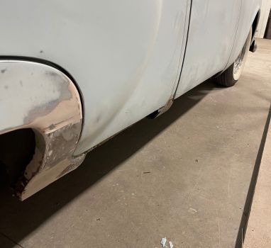 A white car is parked on a concrete floor in a garage.