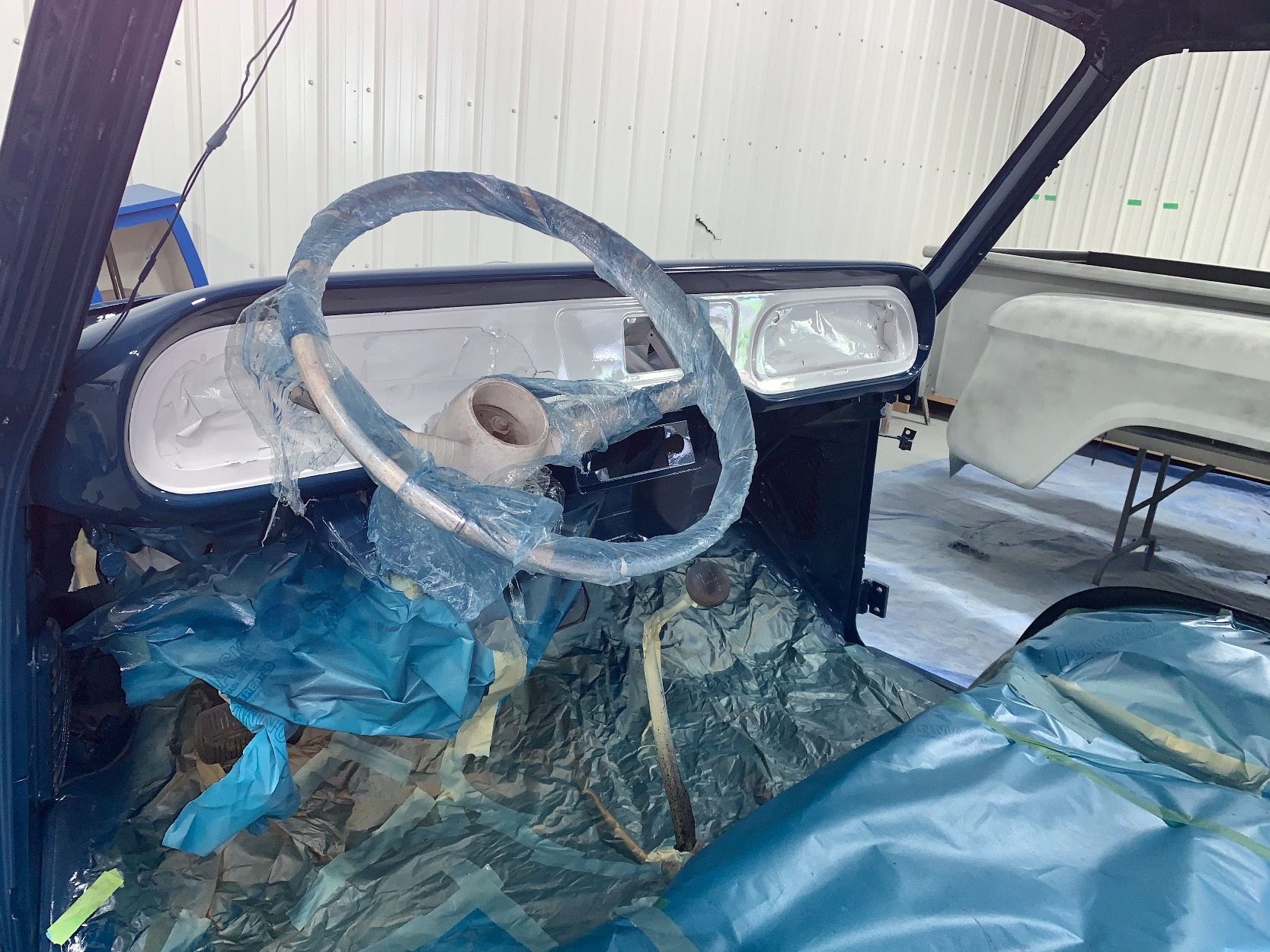 The inside of a car with a steering wheel wrapped in plastic.