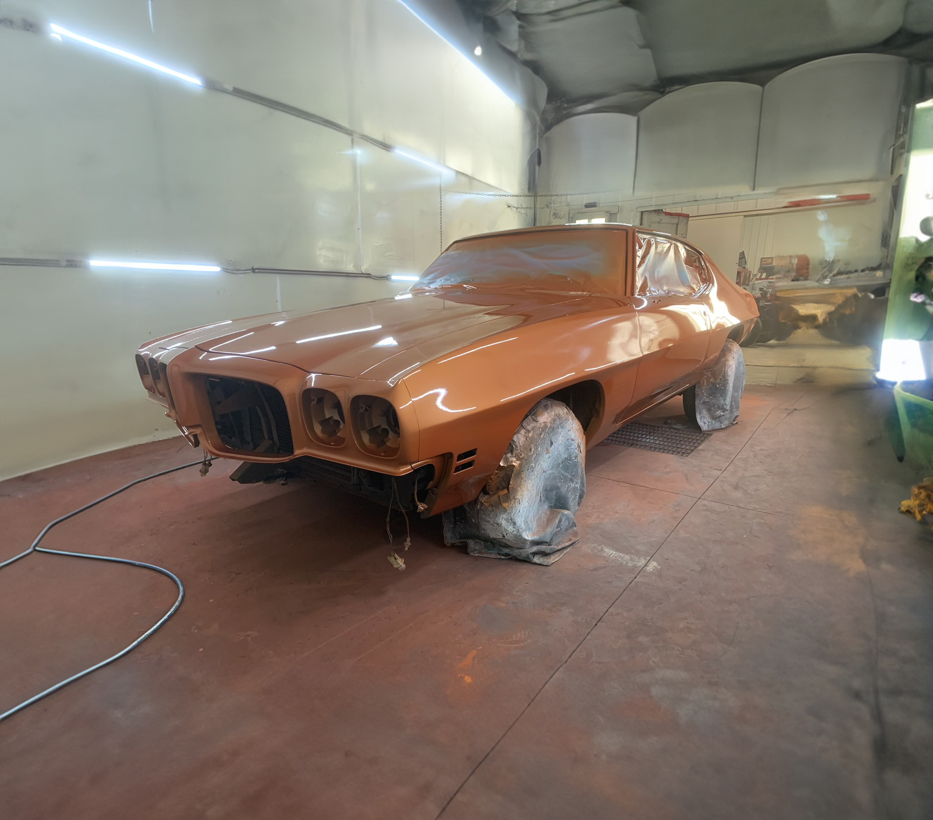 A car is being painted in a garage.