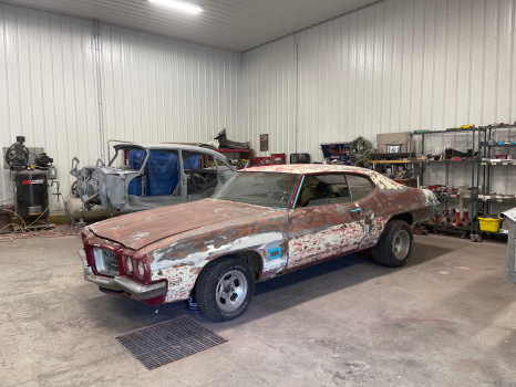 A rusty old car is parked in a garage.