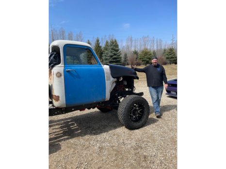 A man is standing next to a blue and white truck.