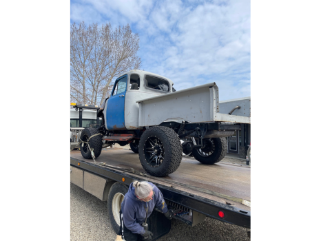 An old truck is being towed by a tow truck.