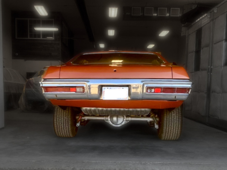An orange car is parked in a dark garage