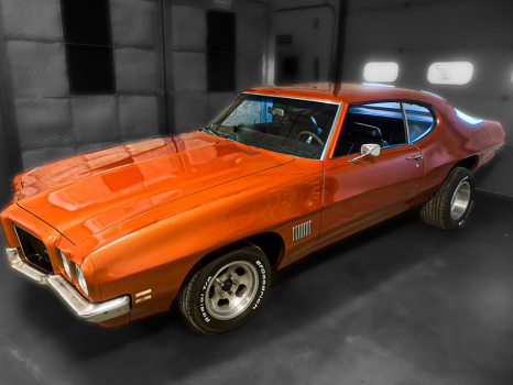 An orange muscle car is parked in a garage.