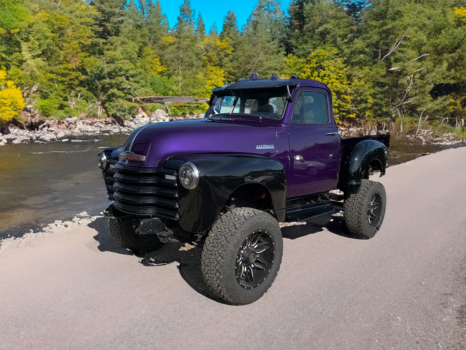 A purple truck is parked next to a river