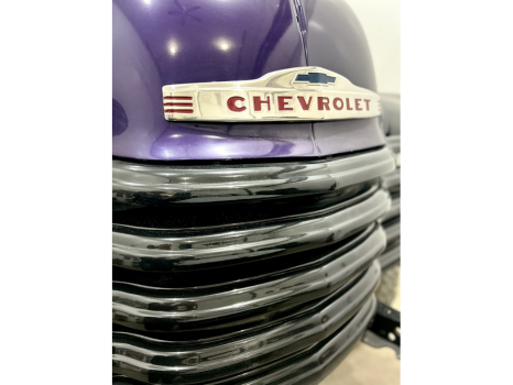 A purple chevrolet truck is parked in a garage.