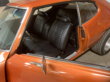 An orange car with black seats is parked in a garage