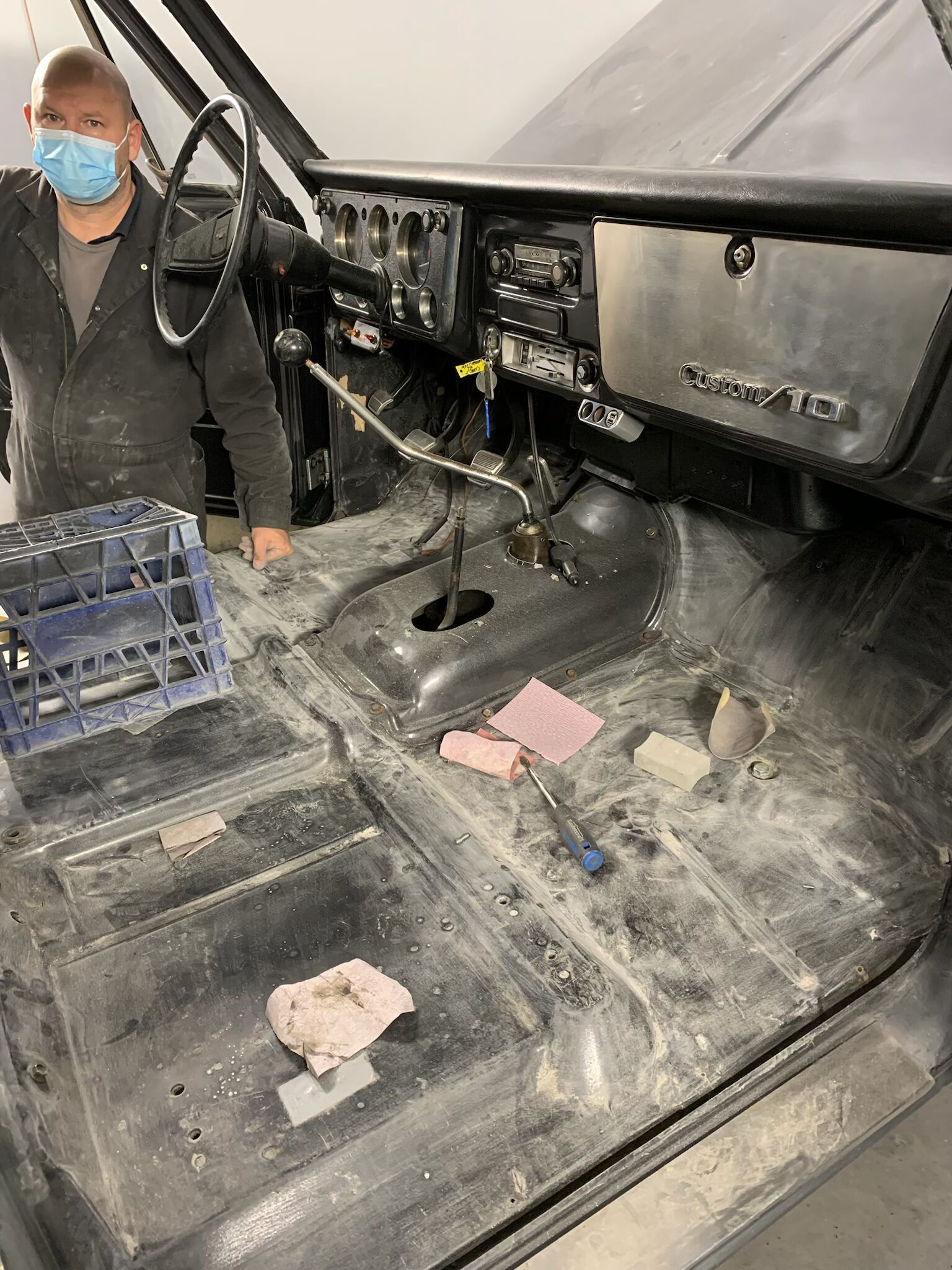 A man wearing a mask is standing in the trunk of a car.