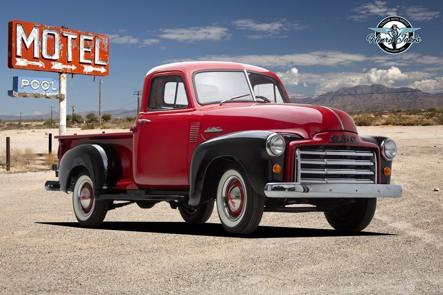 A red truck is parked in front of a motel sign