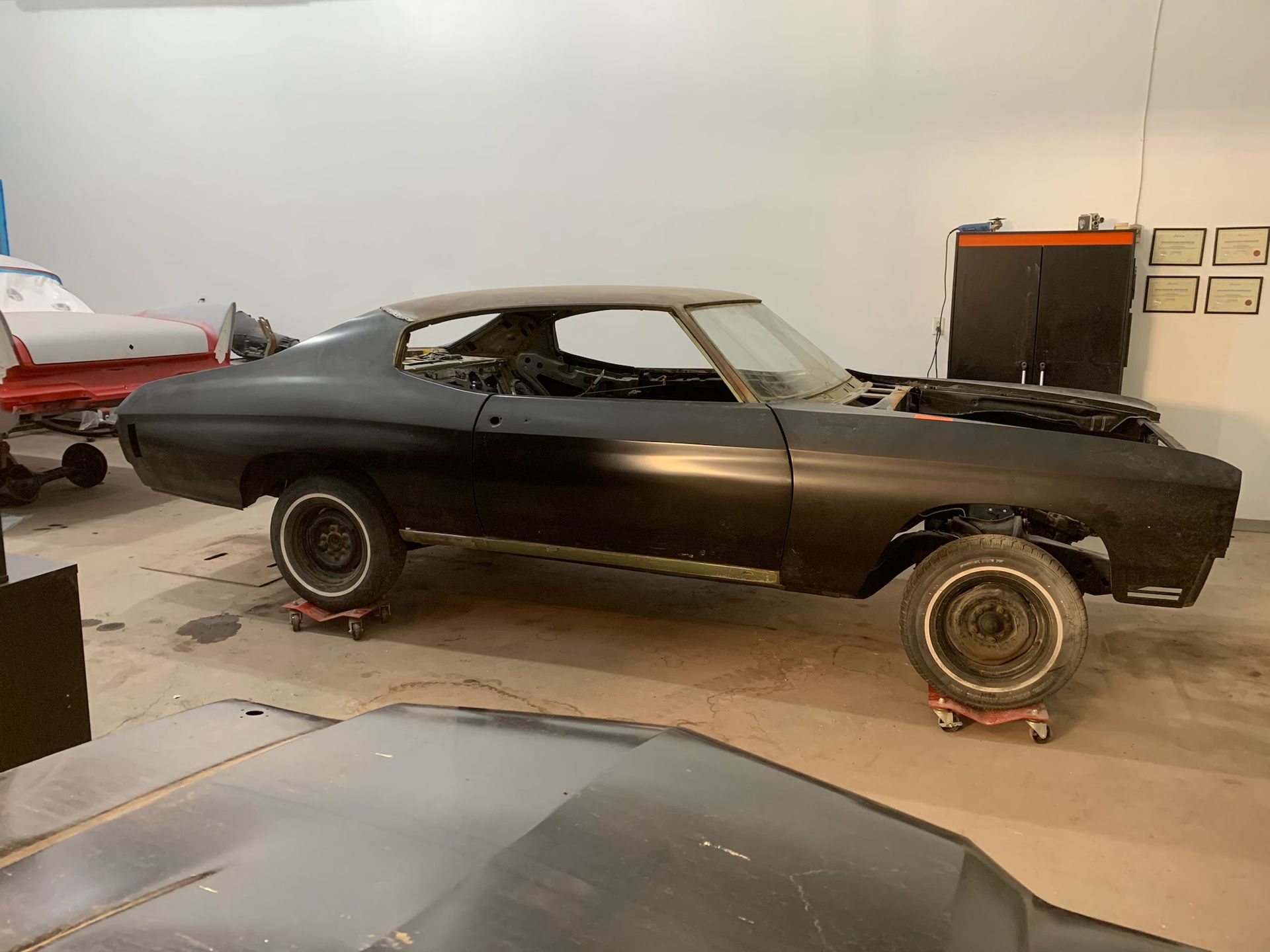 A black car is sitting on wheels in a garage.