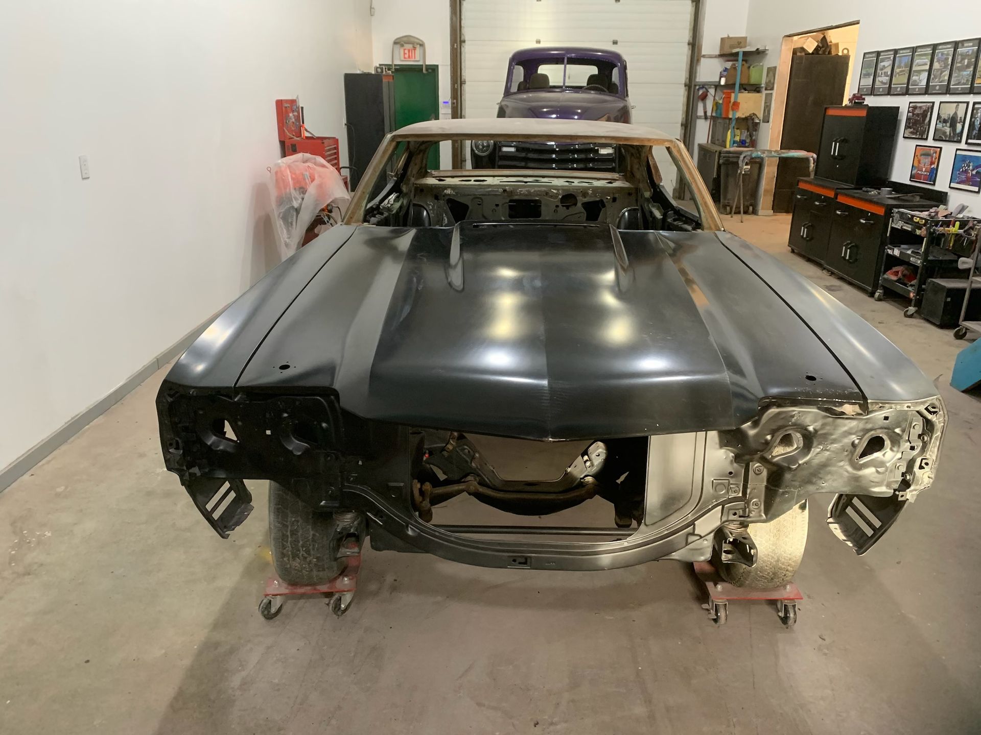 A car with the hood removed is sitting in a garage