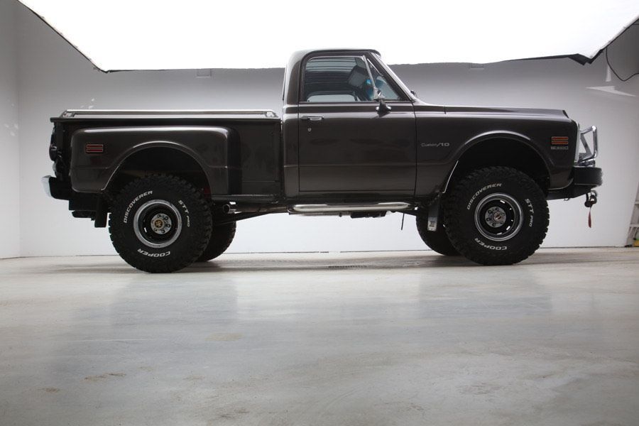 A black truck is parked in a garage with a white background