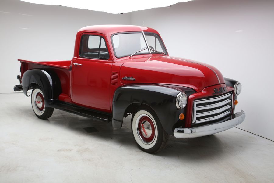 A red and black truck is parked in a white room.