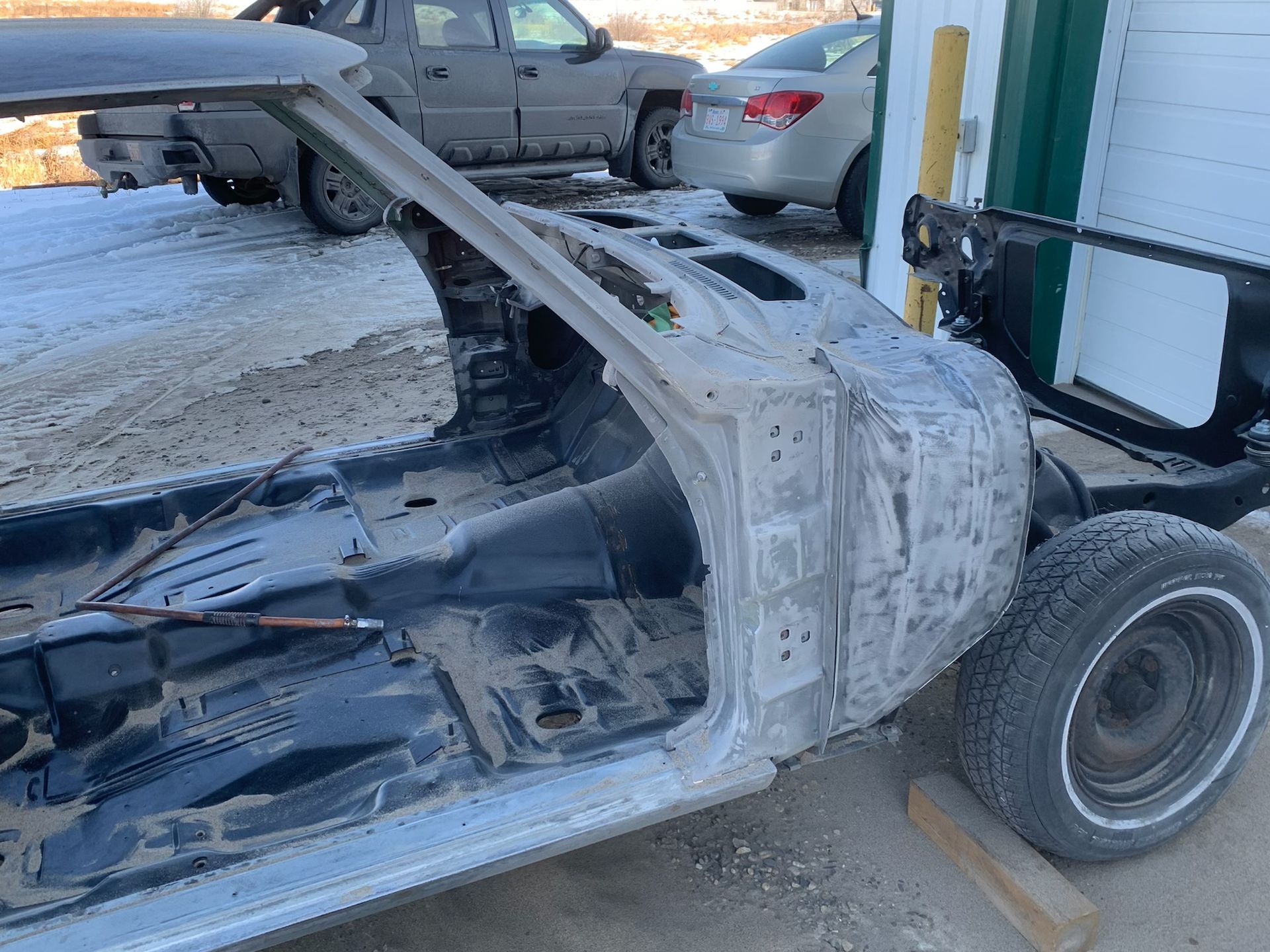 A car is being dismantled in front of a garage.