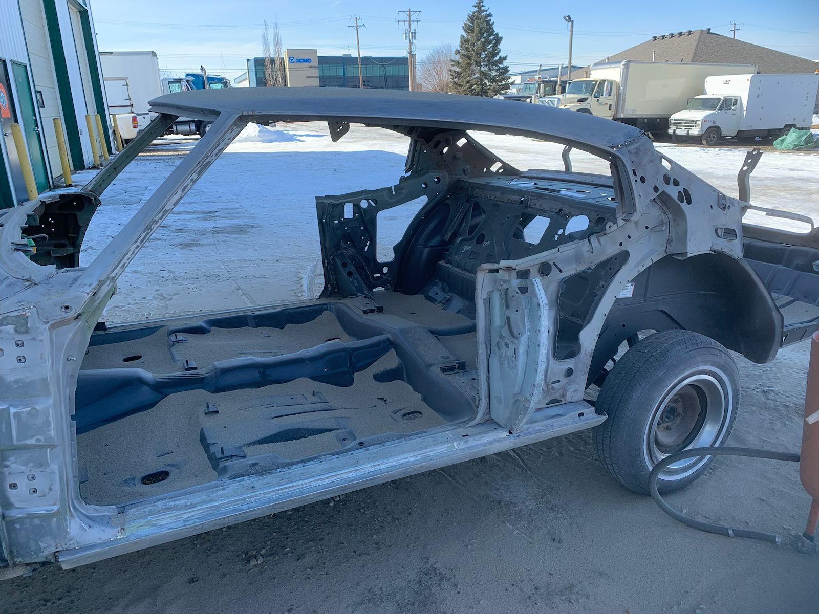 A skeleton of a car is sitting on the ground in a parking lot.