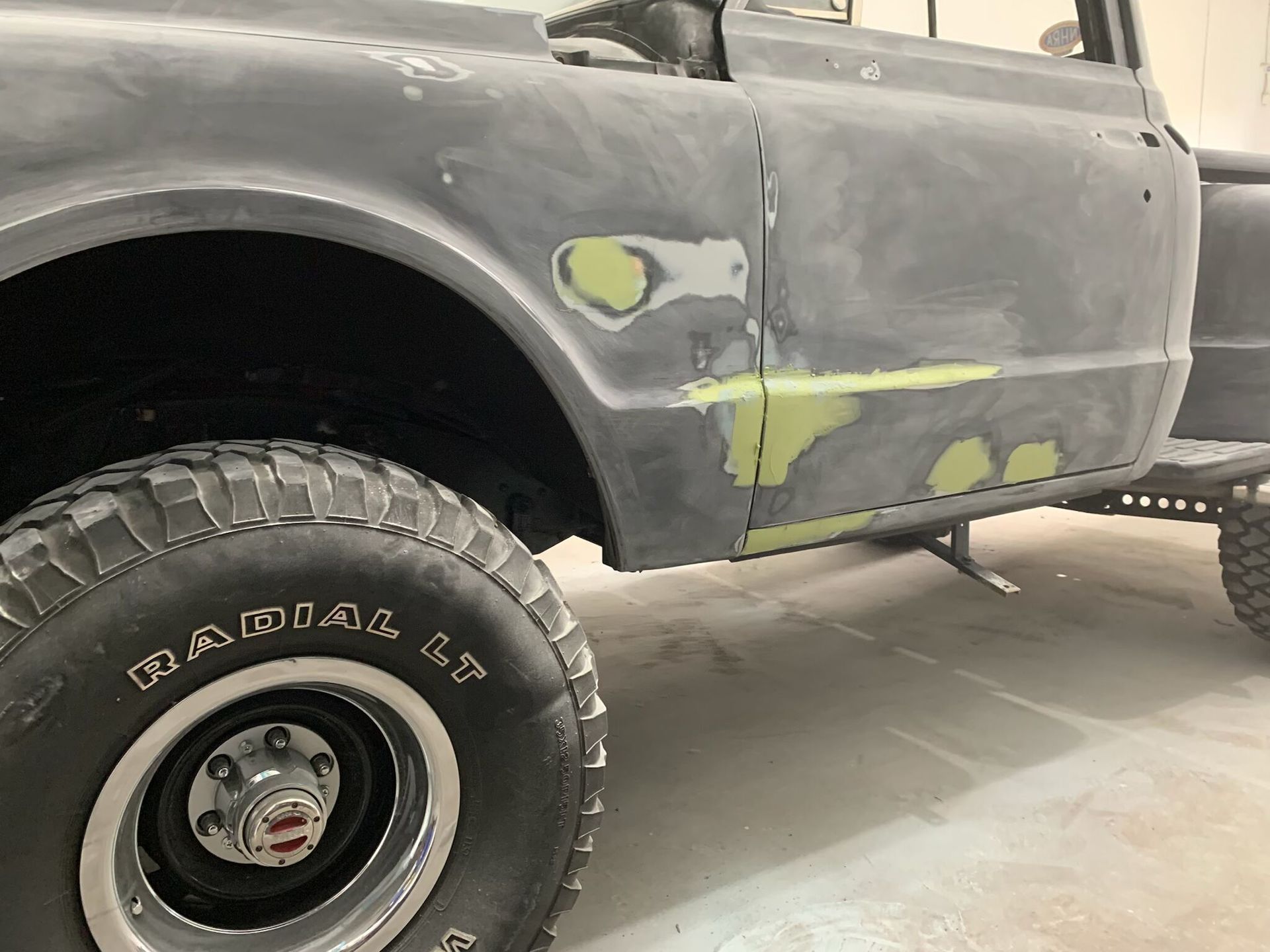 A black truck with a radial tire is parked in a garage.