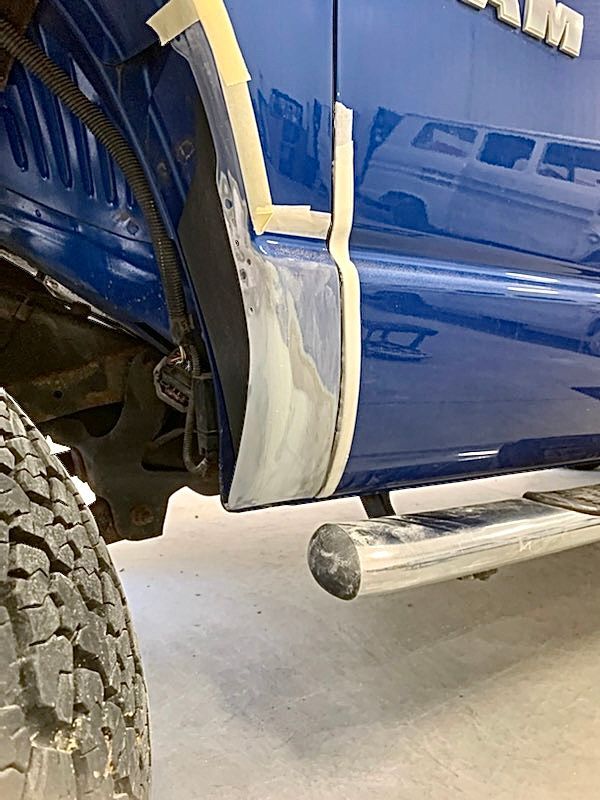 A blue truck is being repaired in a garage.