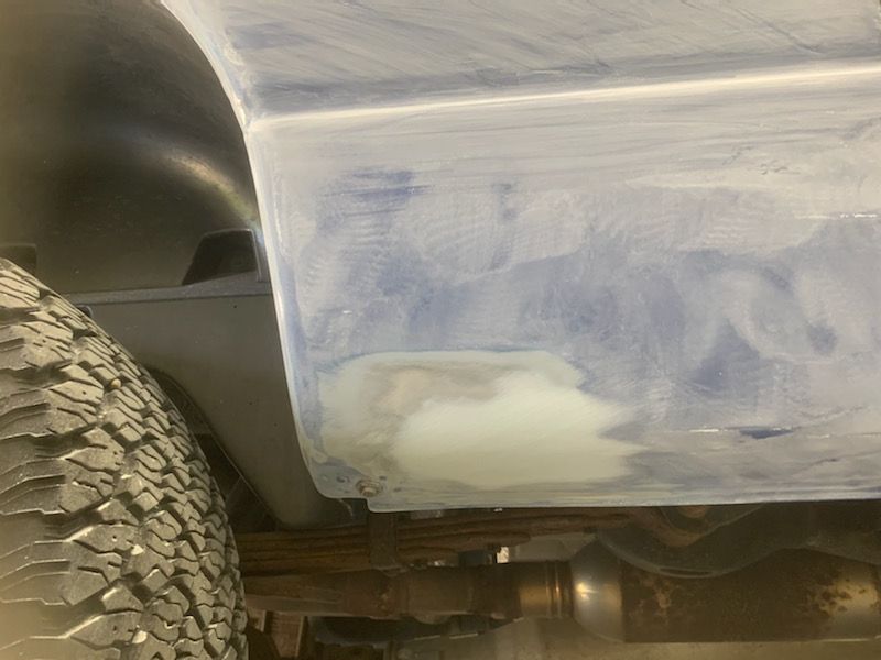 A close up of a car fender with a tire in the background.