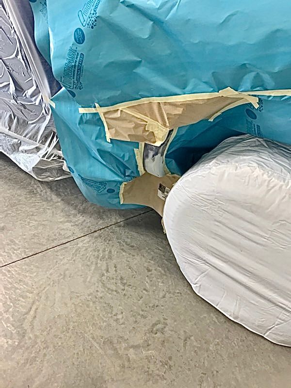 A mattress is wrapped in plastic and tape on the floor.