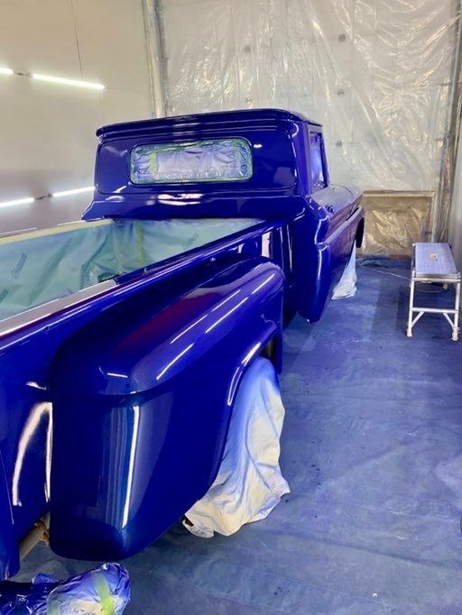 A blue truck is being painted in a garage