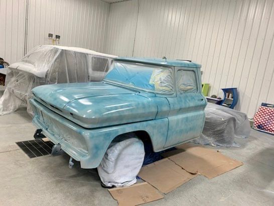 A blue truck is sitting on a cardboard box in a garage.
