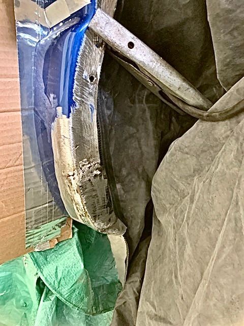 A blue brush is sitting on top of a piece of cardboard.