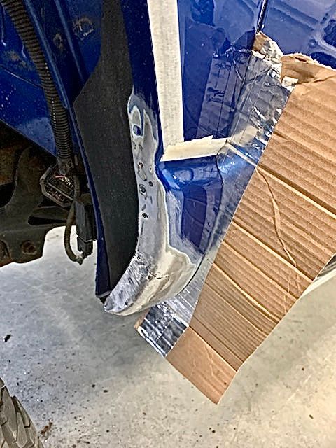 A blue car is sitting on the ground next to a cardboard box.