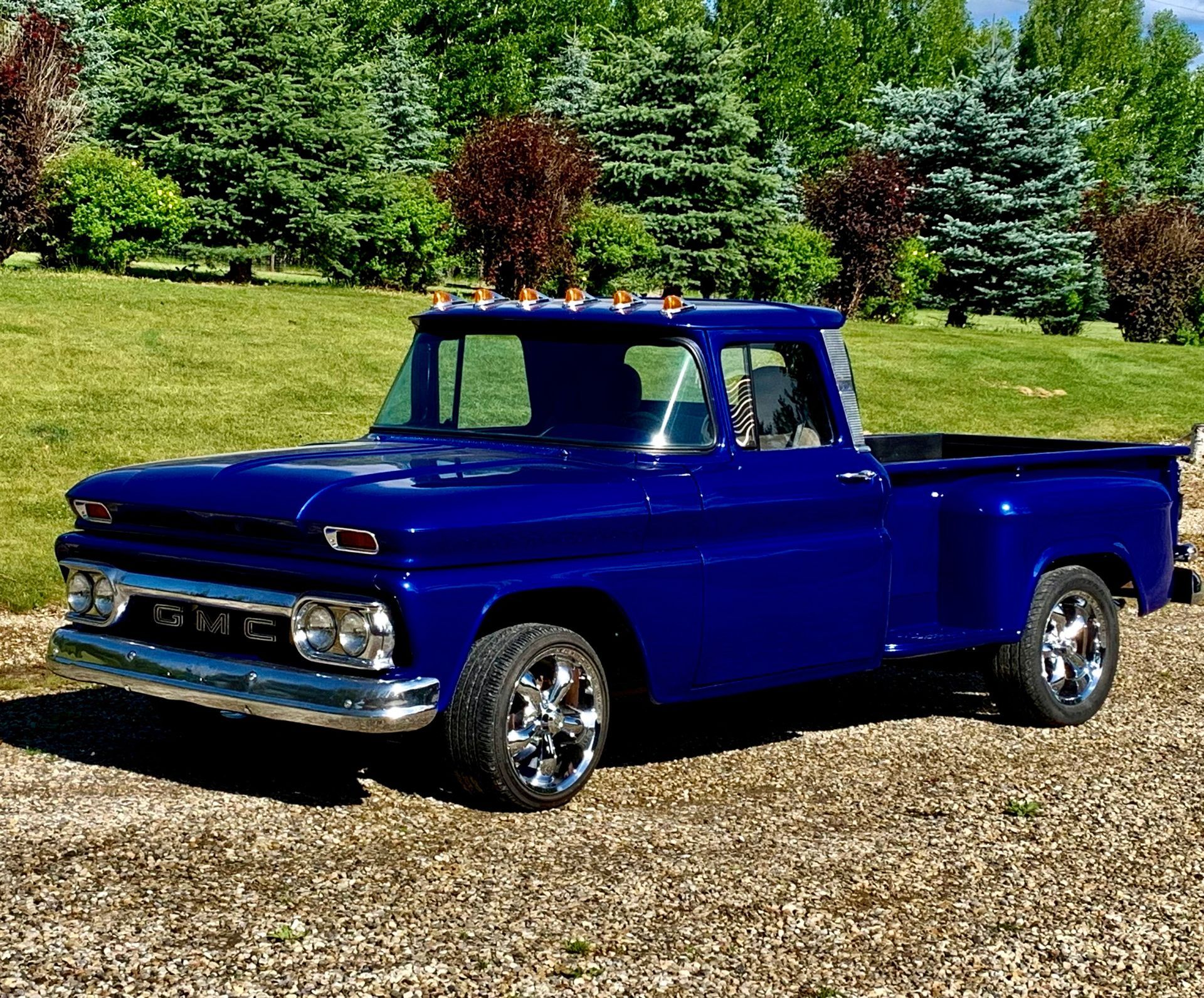A blue pickup truck is parked in a gravel driveway.